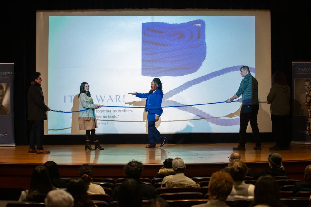 TaRita Johnson points to a person holding a rope with two others on stage